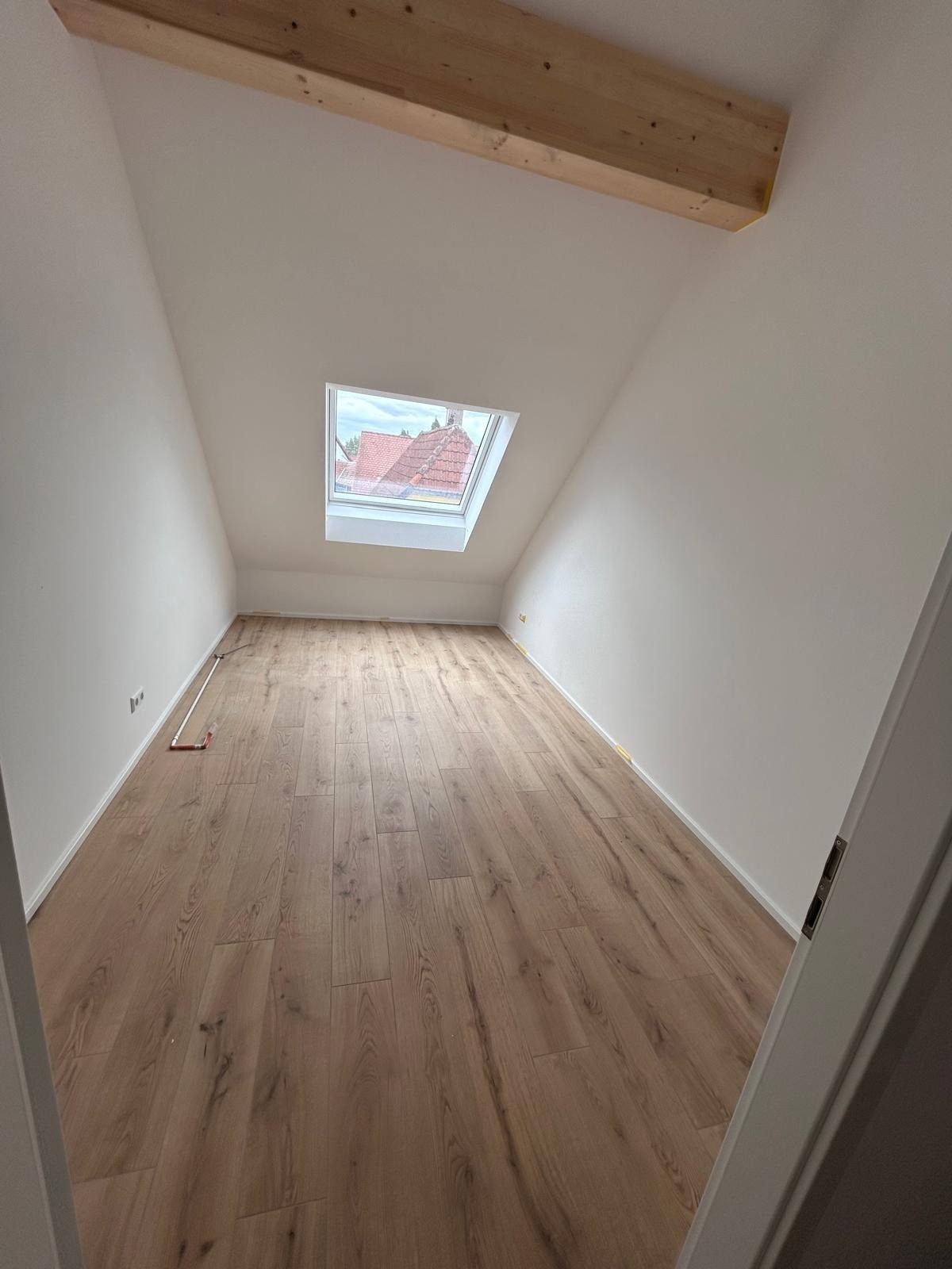 Dachzimmer mit Holzbalken und verlegtem Dielenboden