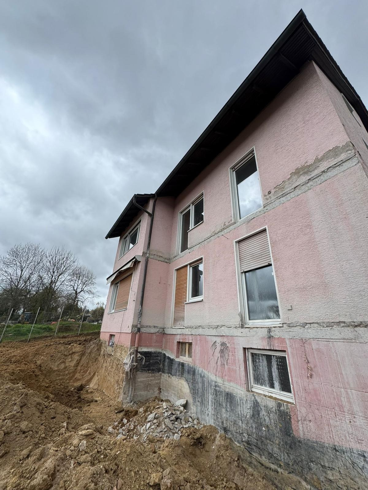 Fassadensanierung mit Sockelabdichtung, Mehrfamilienhaus · Fassade im Rohputz, Erdreich freigelegt